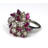 A diamond and ruby dress ring of asymmetrical cluster form, set in white gold or platinum,