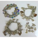 A group of silver charm bracelets, including an example decorated with silver and enamel charms of