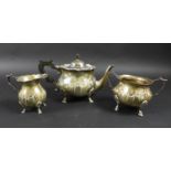 An Edward VII silver three piece tea set, of squat bodied form with scalloped rims, relief decorated