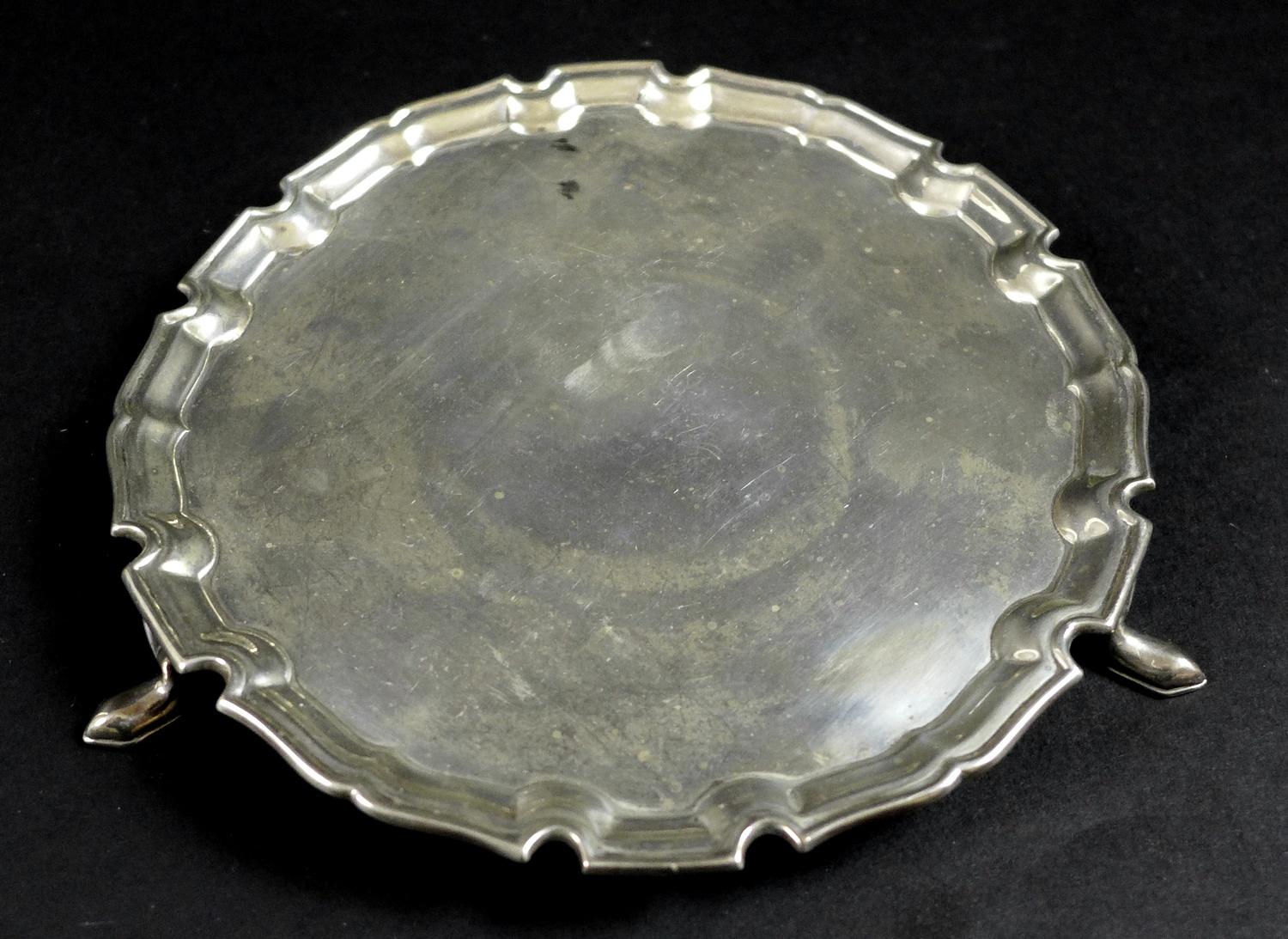 A George V silver waiter tray, of circular form with Chippendale pie crust edge, raised on three