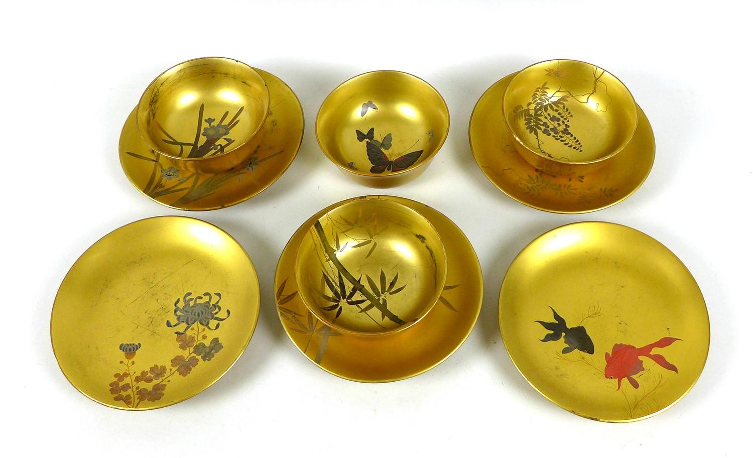 A group of Japanese papier mache, four bowls and five plates, decorated with various motifs