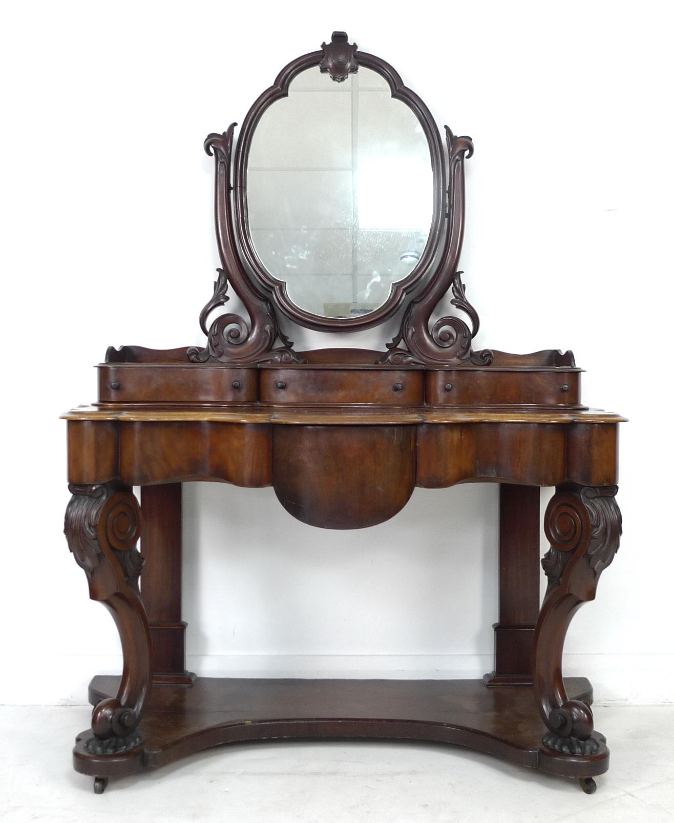 A Victorian mahogany dressing table, with oval mirror on shaped supports, three trinket drawers, the