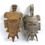 Two Ivory Coast Senufo face masks or Kpelie, of elongated form, with flanges to the sides, the