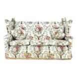 A Knowle style three piece suite, in floral pattern upholstery, comprising a three seater sofa