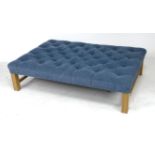 A modern large footstool, with buttoned blue upholstery, raised on oak square section legs and