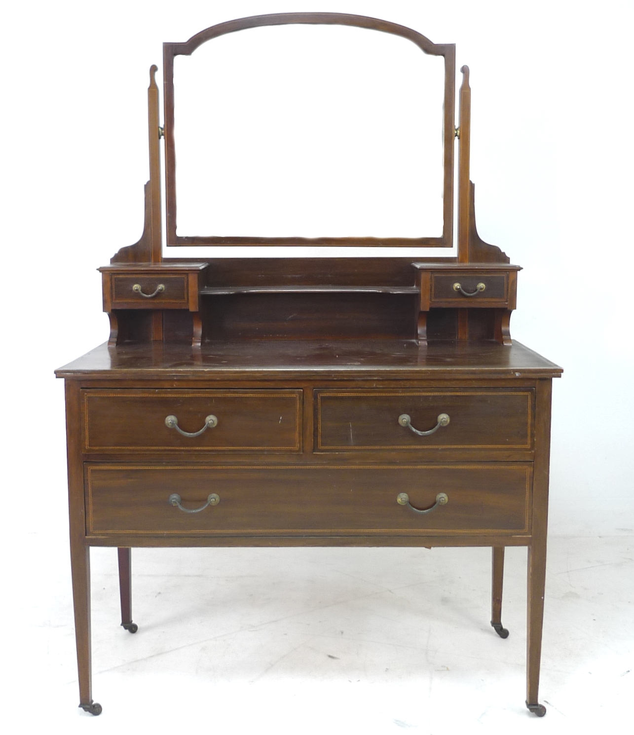 An Edwardian mahogany dressing table, with arched rectangular mirror, trinket drawers, over two
