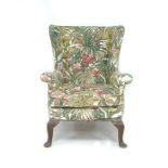 A Parker Knoll wingback armchair, with foliate upholstery, raised upon cabriole legs with pad