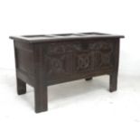 A 17th century oak coffer, the front with three floral carved roundels and scroll frieze above,