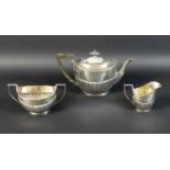 A George V three piece silver tea service, of boat form with part reeded lower bodies, each engraved