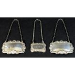 A group of three silver decanter labels, each with cast foliate decorative borders, comprising a