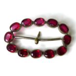 A decorative buckle set with twelve magenta coloured oval 'stones', each 7 by 5 by 3mm, possibly