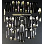 A group of silver and white metal cutlery, including five silver sugar nips, teaspoons, salt spoons,