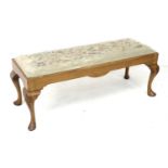A mid 20th century walnut veneered footstool, the rectangular seat embroidered with flowers,