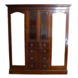 An Edwardian mahogany compactum wardrobe, with outswept cornice over two full height mirrored