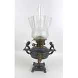 A Victorian cast metal paraffin lamp, with clear glass reservoir on a cast base, decorated in relief