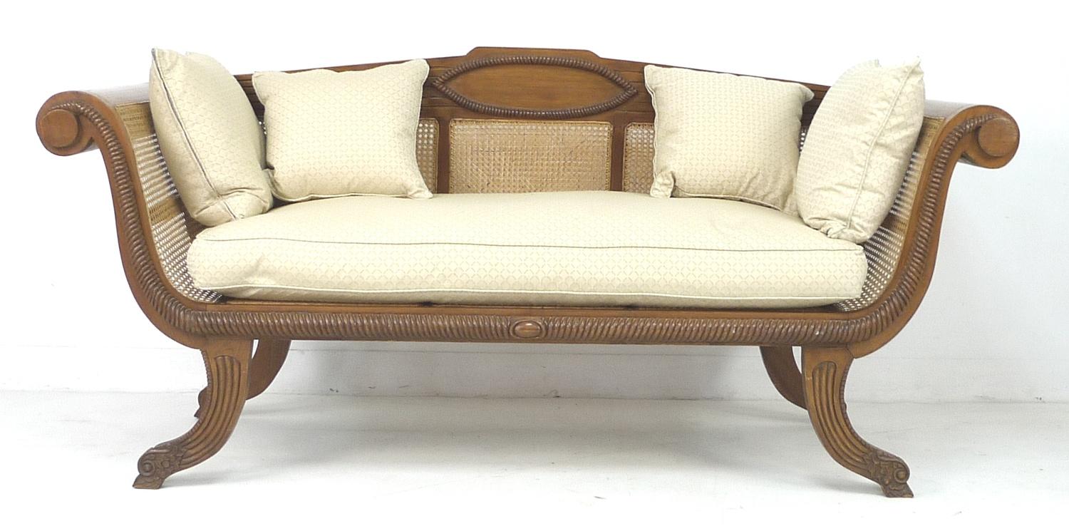 A modern tropical wood bergere settee, with carved frame and scroll arms, caned seat, sides and