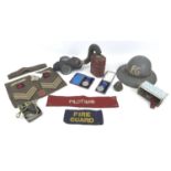 A WWII gas mask, a Fire Guard helmet and arm band, three cap badges, Royal Warwickshire,