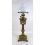 A Victorian brass paraffin lamp, with brass reservoir on a cast floral column, clear glass chimney