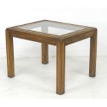 A modern wooden side table, with inset glass surface, carved border, raised on square section