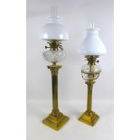 A Victorian brass paraffin lamps, both with clear glass reservoirs on a Corinthian columns and