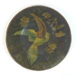 A Victorian paper mache plate, depicting a tropical bird with open wings, surrounded by folliage,