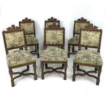 A set of six oak framed dining chairs, with carved top rails, over stuffed upholstered seats and