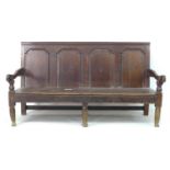 An 18th century oak settle, with four panelled back rest, moulded arm rests, turned supports, and