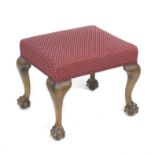 A Victorian footstool with cabriole legs, ball and claw feet, upholstered in red and cream spotted