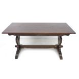 A modern dark stained oak dining table, rectangular surface raised on shaped trestle ends with cut