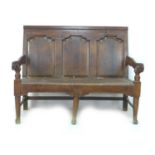 A small 18th century oak settle, with three panelled back rest, moulded armrests, turned supports,