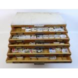 A collection of watch parts, contained within an oak ten drawer table top chest