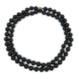 A string of seventy five polished black beads, possibly jet or glass, individually tied, on a 9ct