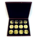 A QEII commemorative coin set, twelve gold plated 50mm coins 'celebrating Her Majesty Queen