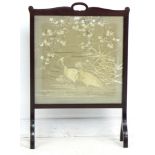 An Edwardian mahogany fire screen, inset with an embroidered panel under glass, depicting two herons