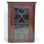 A George III mahogany corner cupboard, single astragal glazed door, three shaped shelves, with