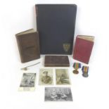 A collection of books, postcards and militaria, including a WWI Victory medal and a Defence medal