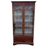 A mahogany bookcase, mid 20th century, with twin arched astragal glazed doors opening to reveal to