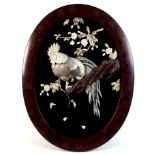 A Japanese oval wall plaque, mid to late 20th century, with relief carved and applied decoration