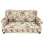 An Edwardian three seater sofa, upholstered in embroidered fabric patterned with large roses, turned