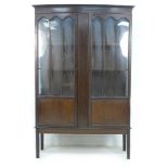 An Edwardian mahogany display cabinet, with gently bowed front, twin glazed doors, two shelves,