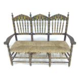 A Spanish painted rush seated three seater settee, early 20th century, with shaped open arms and