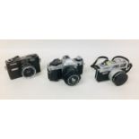 Three Canon cameras, comprising a Canon AE-1 with a Canon FD 50mm 1:1,8 lens, and two Canon