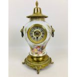 A late 19th century porcelain vase clock, with a brass cover and mounted on circular metal base with