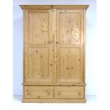 A modern pine wardrobe, two doors with turned handles enclosing a hanging rail, two drawers below,