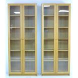 A pair of modern Ikea oak veneered bookcases, each with twin full height glazed doors, with five