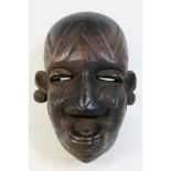 An African Makondo tribal carved wooden mask, depicting a female face with facial scarations, a
