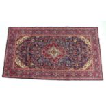 A hand knotted wool Hamadan rug, with central red medallion upon a blue ground and red ground