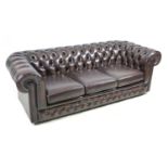 A late 20th century Thomas Lloyd three seater Chesterfield settee in dark brown leather, raised upon