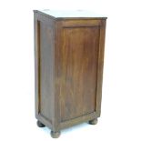 An oak freestanding cupboard, of tall narrow form with sloped lift lid, raised on turned feet, 51 by