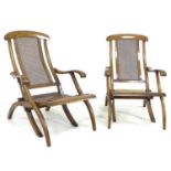A pair of Edwardian stained beech folding ?steamer? style deck chairs, with caned seats and backs,